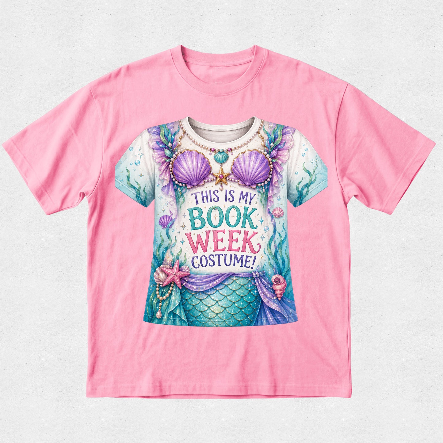 A pink short-sleeve crewneck t-shirt featuring a colorful graphic of a mermaid in a book-themed costume with the text 'THIS IS MY BOOK WEEK COSTUME!'.