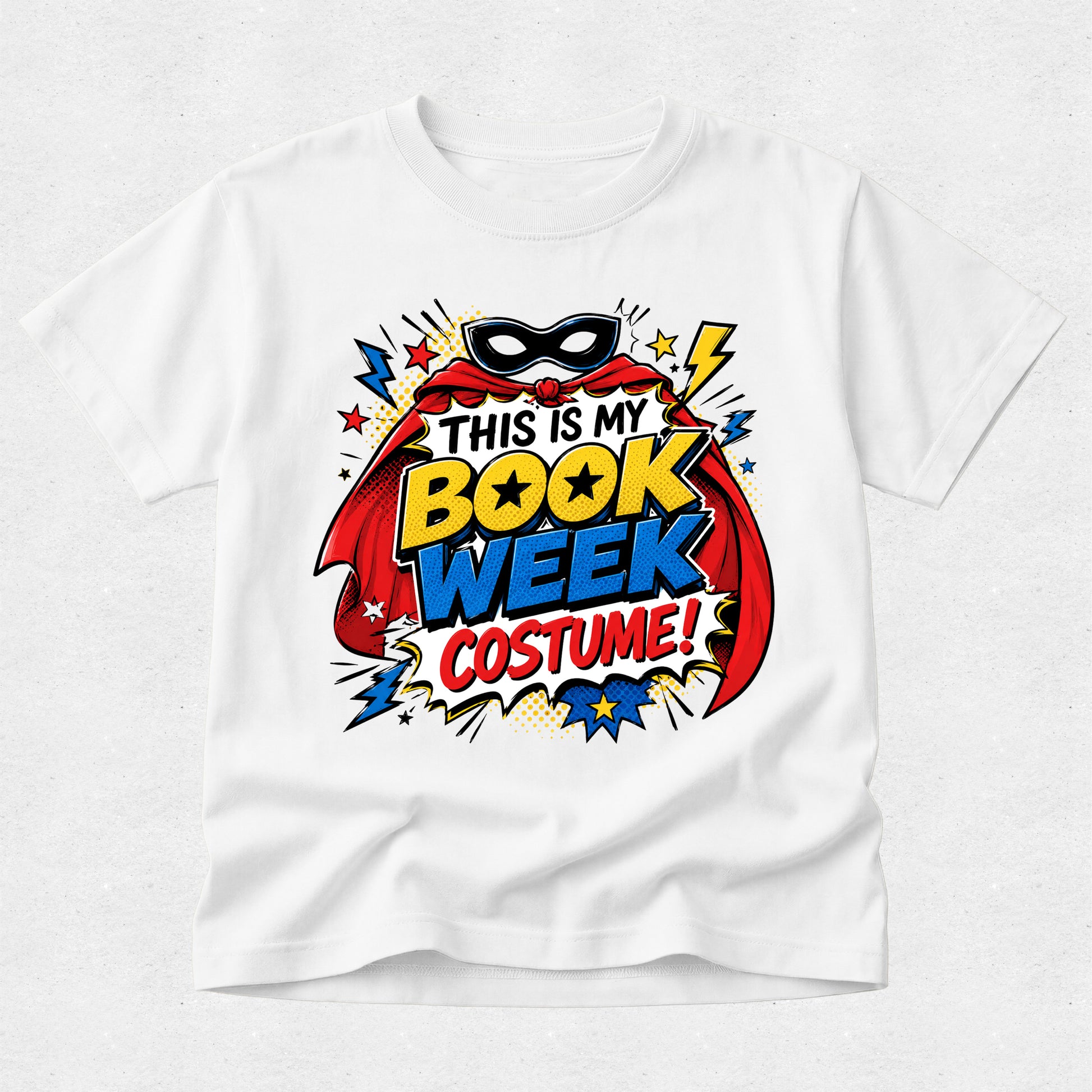 A white short-sleeve crewneck t-shirt featuring a colorful comic book style graphic on the chest that reads 'THIS IS MY BOOK WEEK COSTUME!' with a superhero mask, cape, stars, and comic-style text elements.