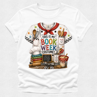 A white short-sleeve crewneck T-shirt featuring a colorful graphic print of a chef costume shirt with the text 'THIS IS MY BOOK WEEK COSTUME!' and illustrated cooking-themed props like utensils, books, a whisk, and a mug.