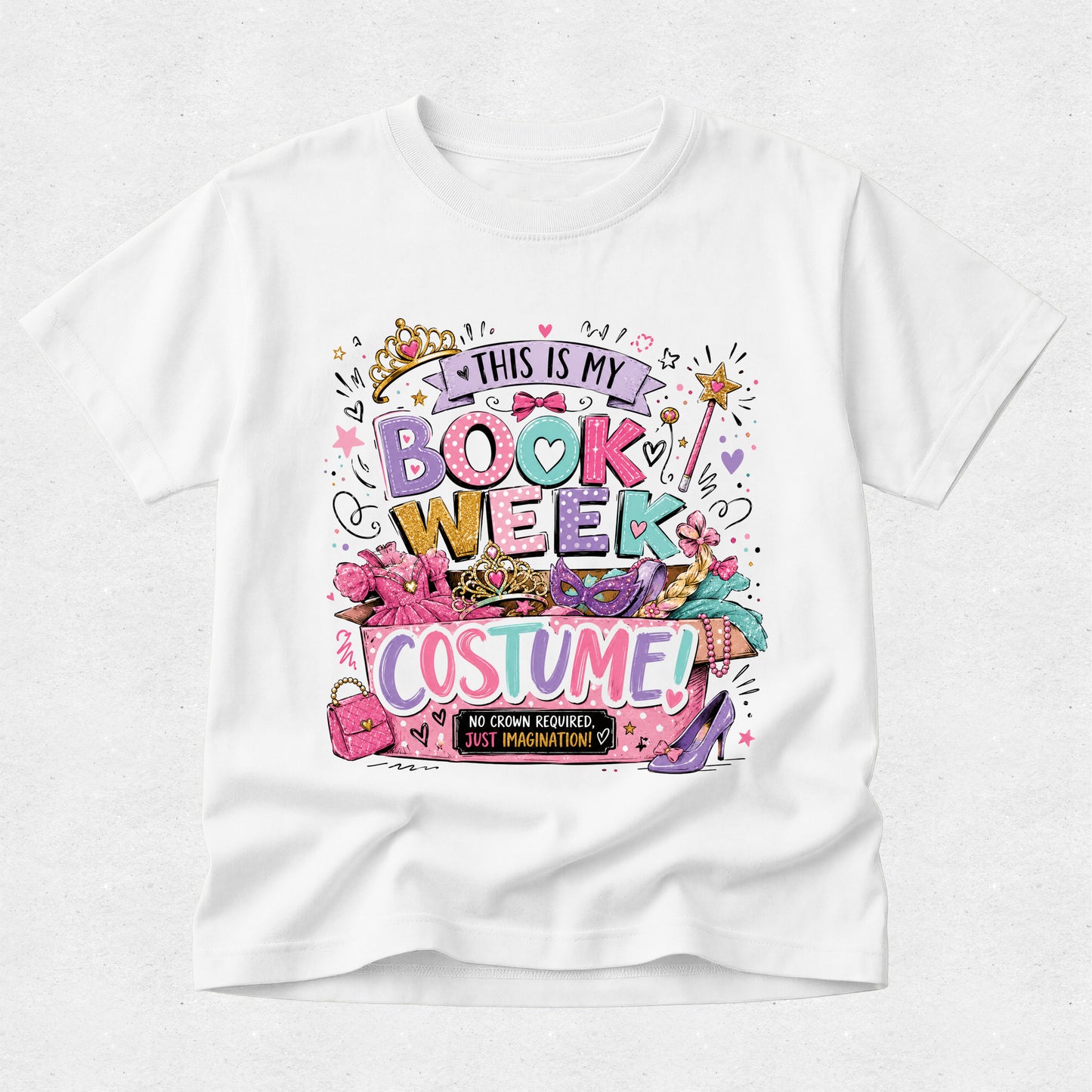 A white short-sleeve crewneck t-shirt featuring a colorful graphic print on the front that reads 'THIS IS MY BOOK WEEK COSTUME!' surrounded by illustrations of a crown, pink heels, a wand, and shopping bags.