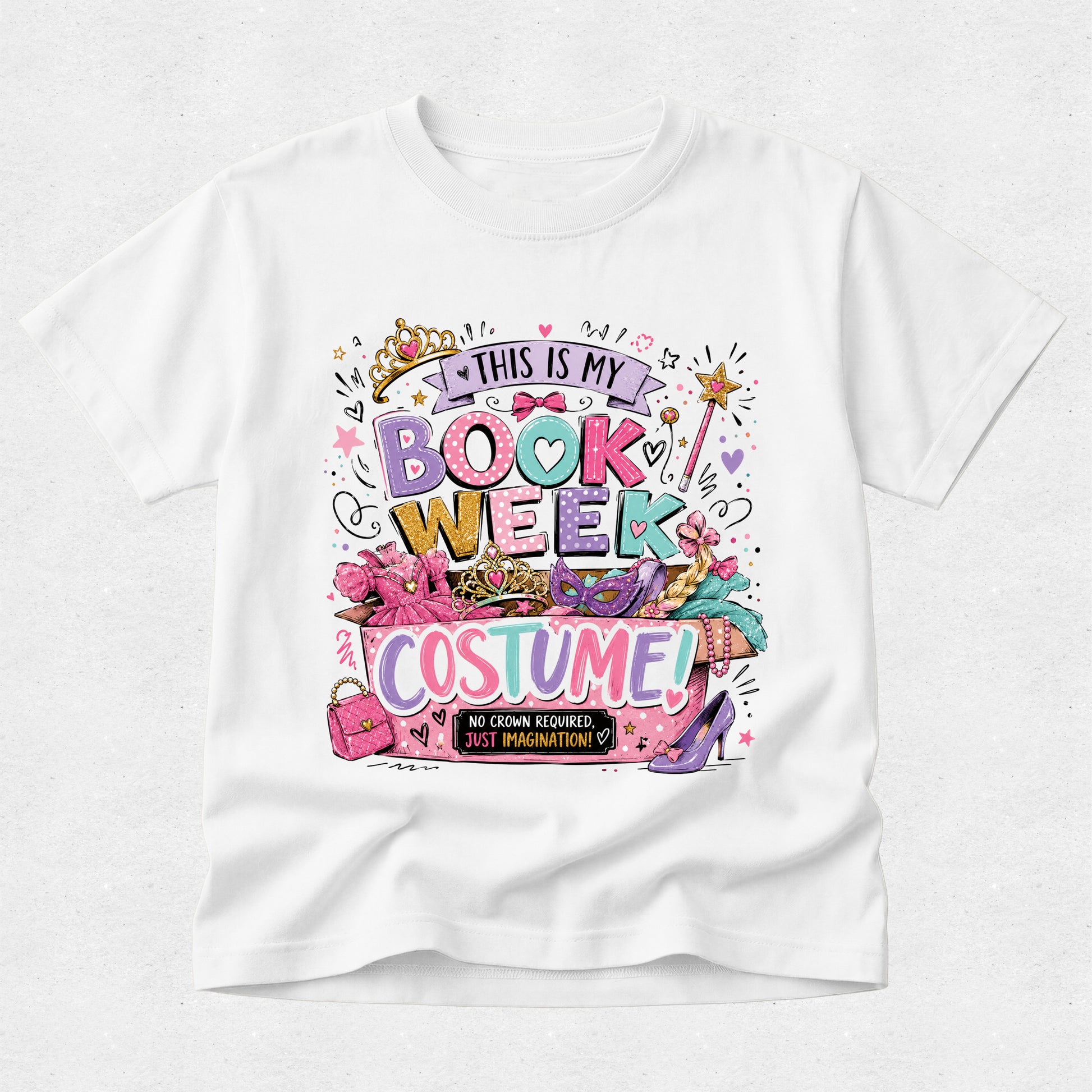 A white short-sleeve crewneck t-shirt featuring a colorful graphic print on the front that reads 'THIS IS MY BOOK WEEK COSTUME!' surrounded by illustrations of a crown, pink heels, a wand, and shopping bags.