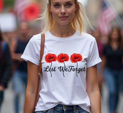 Woman wearing a white t-shirt with red poppies and 'Lest We Forget' text in a crowd.