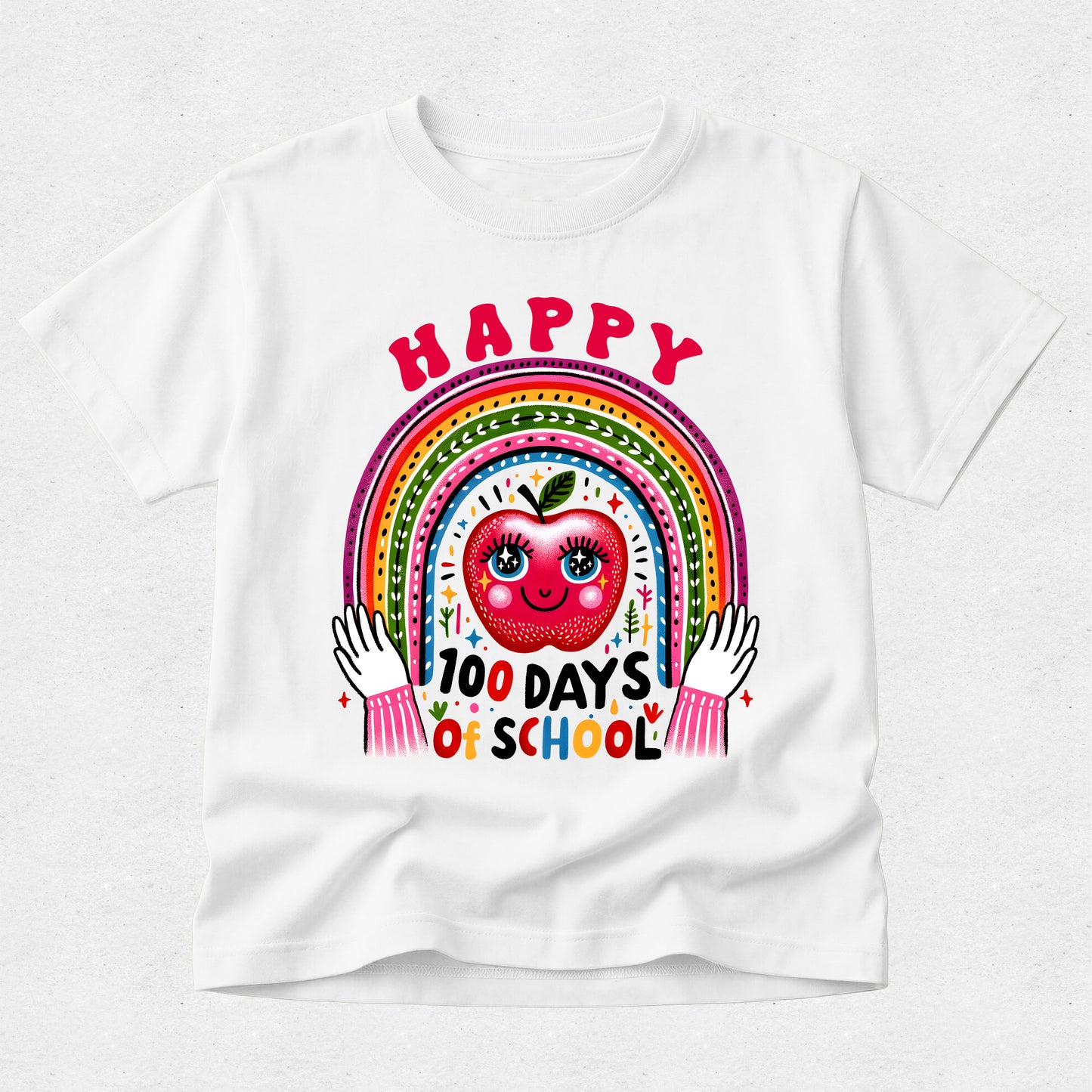 A white short-sleeve t-shirt with a colorful graphic on the front featuring a smiling red apple, a rainbow, and the text 'HAPPY 100 DAYS OF SCHOOL'.