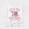 A white short-sleeve t-shirt with a pink and silver graphic that reads 'IT'S MY 1st BIRTHDAY #Double Digits' featuring a pink bow and disco ball design, shown on a light gray textured background.
