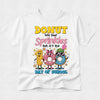 A white short-sleeve t-shirt with a colorful graphic on the front that reads 'DONUT lose your Sprinkles but it's the DAY OF SCHOOL' above three cartoon donuts wearing sunglasses and hats, shown on a light gray background.