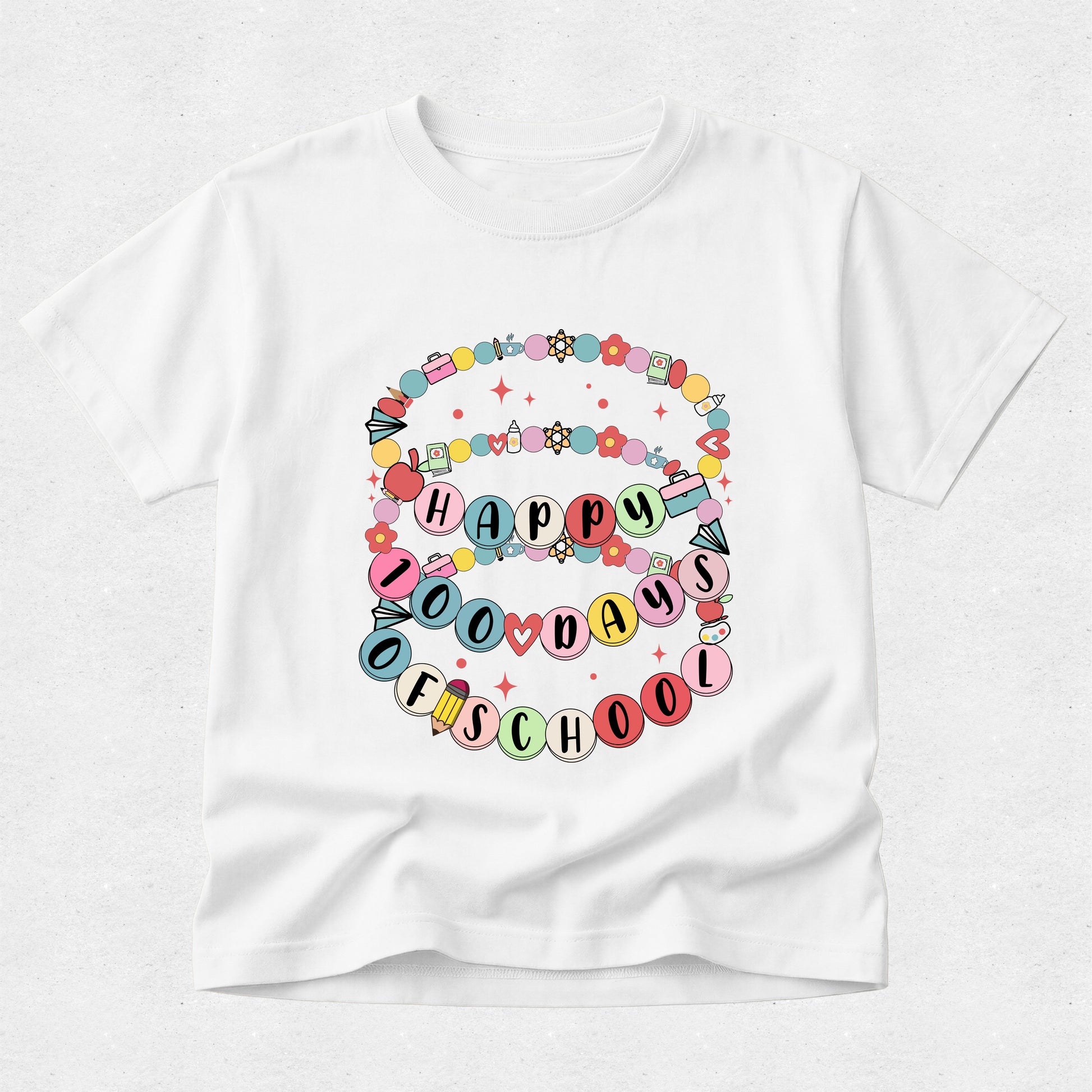 A white short-sleeve crewneck t-shirt featuring a colorful graphic on the front that reads 'HAPPY 100 DAYS OF SCHOOL' in pastel-colored letters, surrounded by decorative balloons, stars, and flowers.