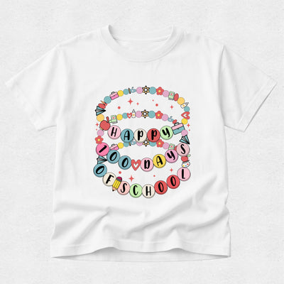 A white short-sleeve crewneck t-shirt featuring a colorful graphic on the front that reads 'HAPPY 100 DAYS OF SCHOOL' in pastel-colored letters, surrounded by decorative balloons, stars, and flowers.