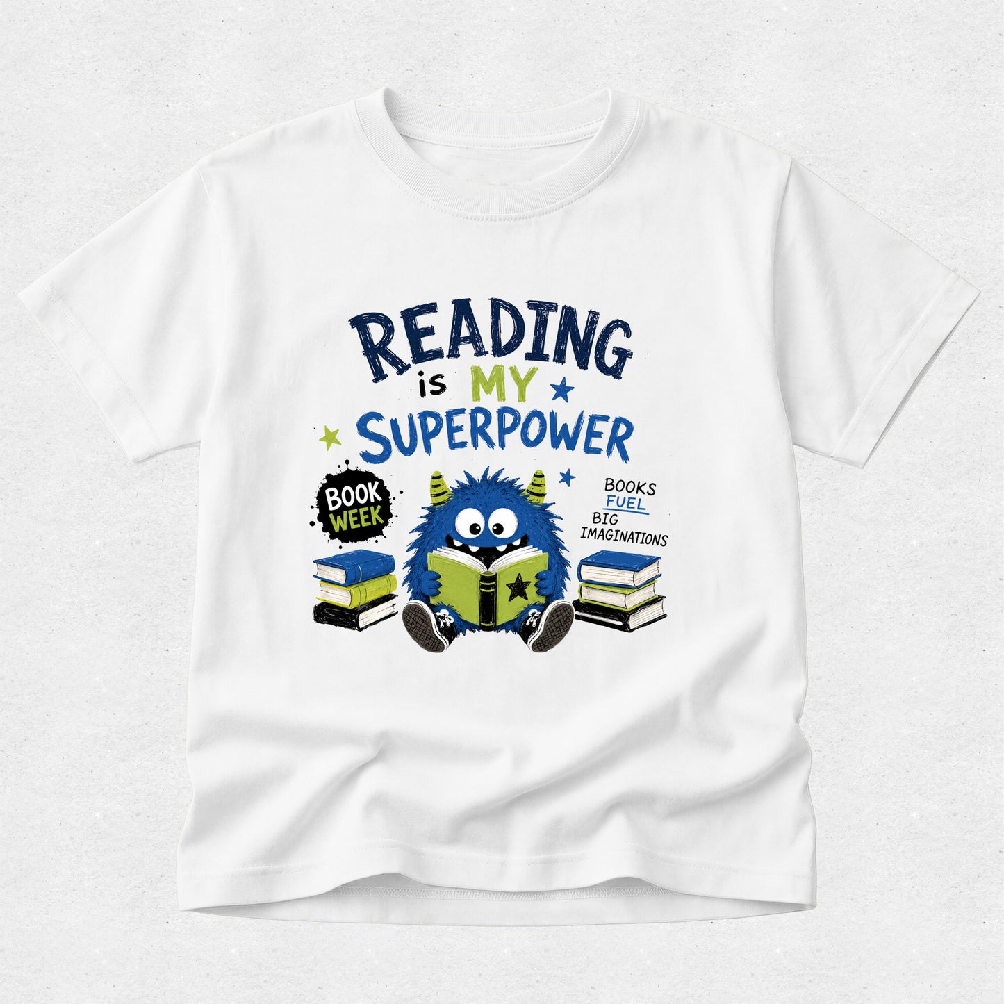 A white short-sleeve crewneck t-shirt featuring a colorful graphic design on the front. The graphic reads 'READING is MY SUPERPOWER' in dark blue and yellow lettering, accompanied by a cute blue monster reading a green book, stacks of books, and a 'BOOK WEEK' badge, all set against a light gray textured background.