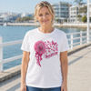 Woman wearing a white breast cancer awareness T-shirt with a heart design made of pink ribbons, flowers and hearts.