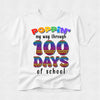 A white short-sleeve t-shirt with a colorful graphic that reads 'POPPIN' my way through 100 DAYS of school' on a light gray background.