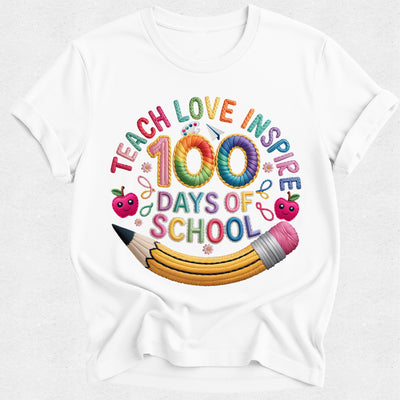 A white short-sleeve crewneck t-shirt featuring a colorful graphic design on the front. The design reads 'TEACH LOVE INSPIRE 100 DAYS OF SCHOOL' in playful, multi-colored lettering, decorated with cartoon apples, a yellow pencil, and small pink flowers.