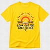 A bright yellow short-sleeve t-shirt with a retro-style sun graphic and the text 'LOOK OUT FOR EACH OTHER' printed on the front, displayed flat against a light textured background.