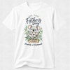 A white short-sleeve crewneck t-shirt featuring a watercolor-style graphic of a koala holding a baby koala, surrounded by green leaves. The text reads 'Our First Father's Day' and 'Daddy & Samuel 2026'.