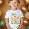 Child wearing a white t-shirt with animal graphics and the text 'Wild ONE' amidst balloons.