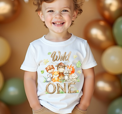 Child wearing a white t-shirt with animal graphics and the text 'Wild ONE' amidst balloons.