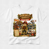 A white short-sleeve crewneck t-shirt featuring a colorful graphic print on the front. The graphic is titled 'Book Week Quest Rescue Heroes' and depicts a young firefighter character with a helmet and megaphone, surrounded by a fire station, ambulance, helicopter, and a Dalmatian dog.