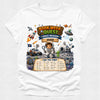 A white short-sleeve crewneck t-shirt featuring a colorful cartoon graphic of a 'Book Week Quest Space Mission' themed around the book 'Susi' by Susie. The graphic includes illustrations of an astronaut, a rocket ship, a space rover, a UFO, and a checklist at the bottom.