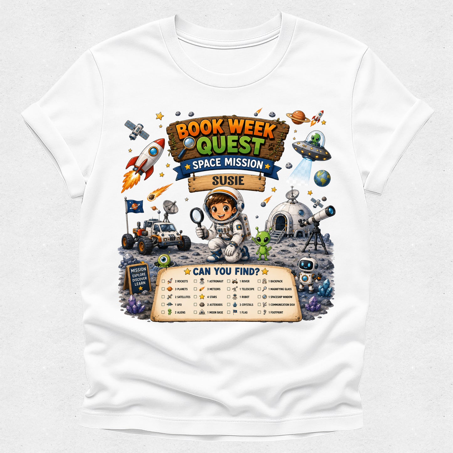 A white short-sleeve crewneck t-shirt featuring a colorful cartoon graphic of a 'Book Week Quest Space Mission' themed around the book 'Susi' by Susie. The graphic includes illustrations of an astronaut, a rocket ship, a space rover, a UFO, and a checklist at the bottom.
