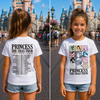 A young girl is shown in a split front-and-back view wearing a white graphic T-shirt and denim shorts in front of a castle, with the shirt featuring the text 'PRINCESS THE ERAS TOUR' and character illustrations on the front, and a list of dates and locations on the back.