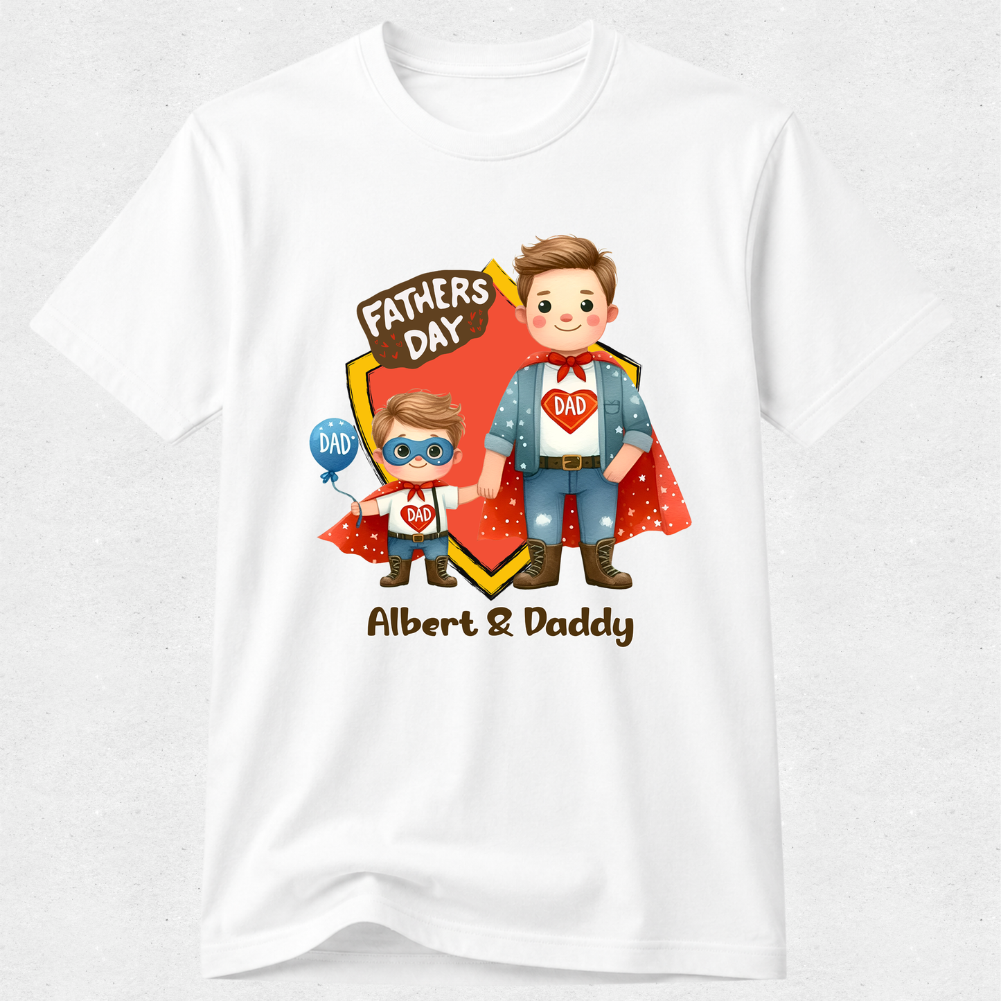 A white short-sleeve crewneck t-shirt with a colorful graphic on the front. The graphic features cartoon illustrations of a father and son dressed as superheroes, with a red shield, a 'FATHERS DAY' banner, and the text 'Albert & Daddy' printed below.