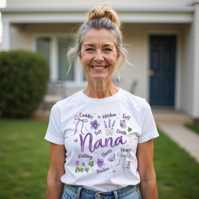 Woman wearing a nana white t-shirt with purple text and graphics, standing outdoors.