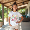 Young girl wearing a easter kpop white t-shirt with colorful graphics and text, standing outdoors.