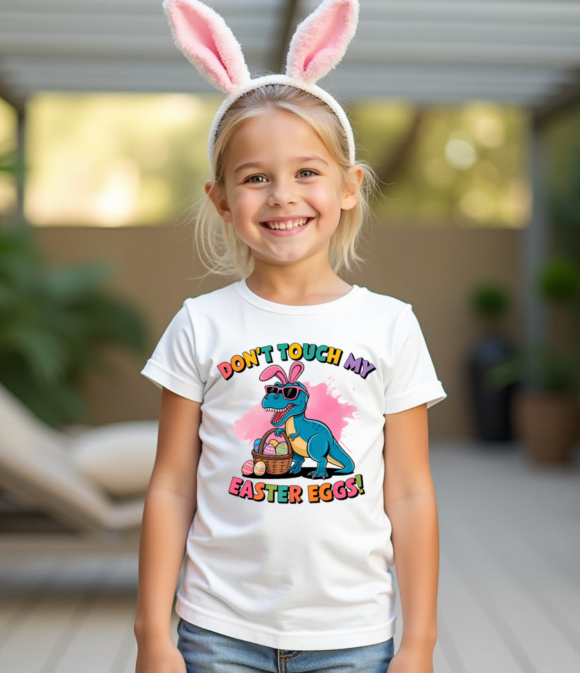 Child wearing a white t-shirt with a cartoon character and Easter text, smiling outdoors.