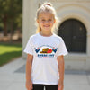 Young girl wearing a white t-shirt with ANZAC Day design outdoors.