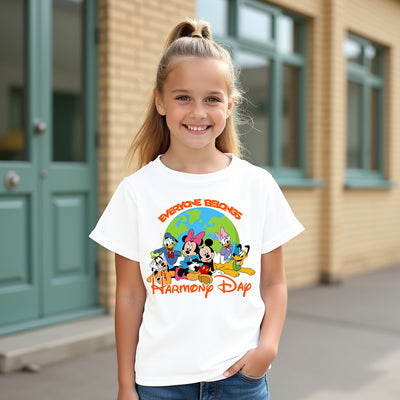 Young girl wearing a white t-shirt with disney mickey characters and text, standing in front of a building.