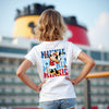 Person wearing a white t-shirt with colorful graphics in front of a cruise ship.