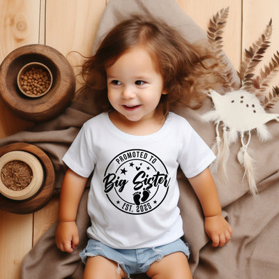 Young girl wearing “Promoted to Big Sister” tee, ideal for baby reveals, photoshoots, and sibling pride.