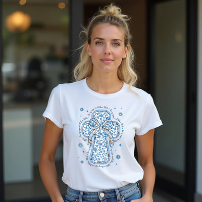 Woman wearing a white t-shirt with a blue cross design outdoors.