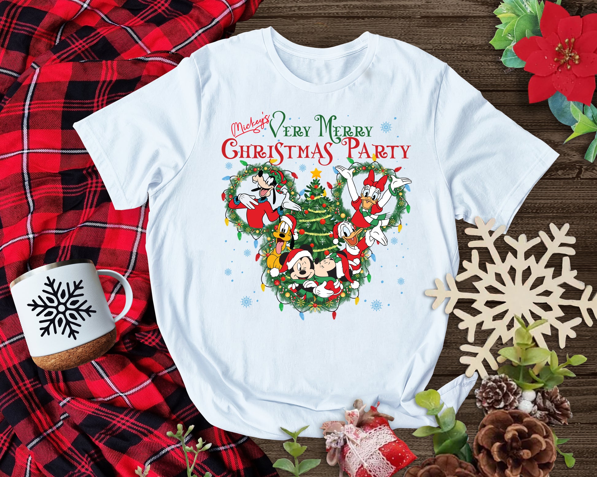 White t-shirt with Christmas-themed design on a wooden surface with festive decorations.