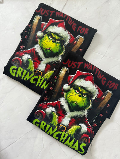 Flat lay of Just Waiting for Grinchmas Tshirt with Christmas decorations and accessories.
